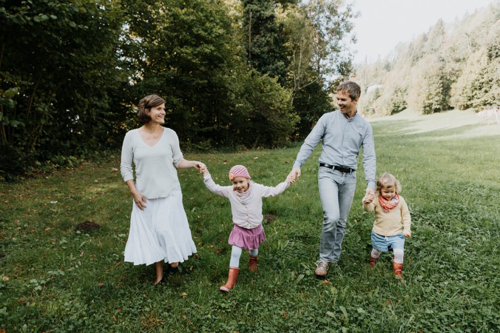 Natürliche Familienfotografie Vorarlberg: Familie spaziert in Garten