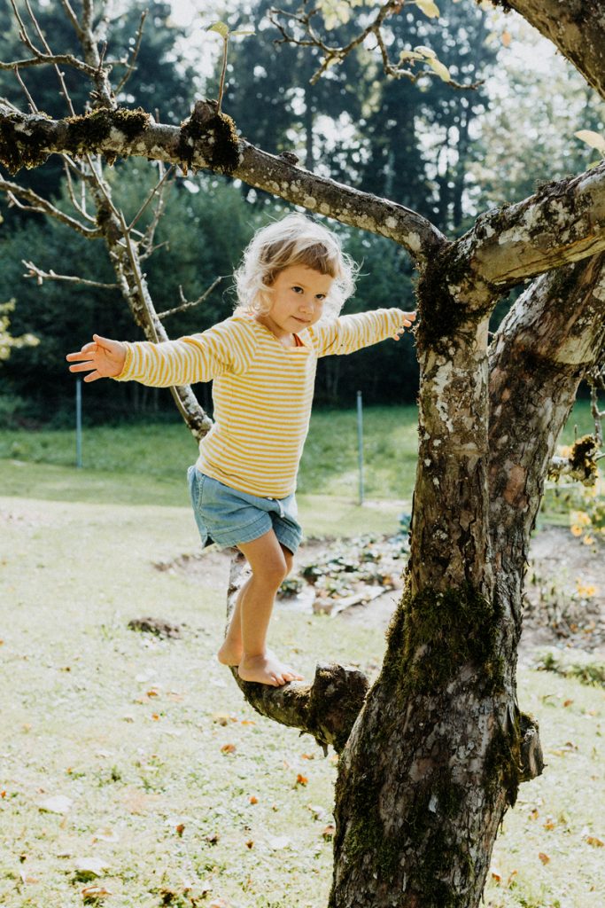Portrait von Mädchen wie es am Baum balanciert