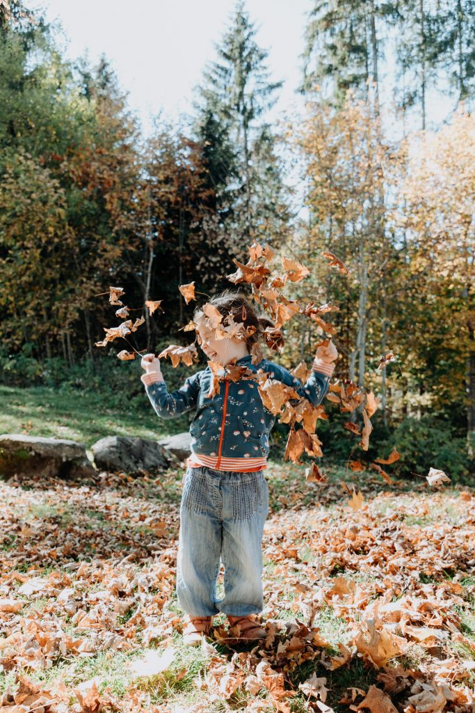 Mädchen spielt mit Laub